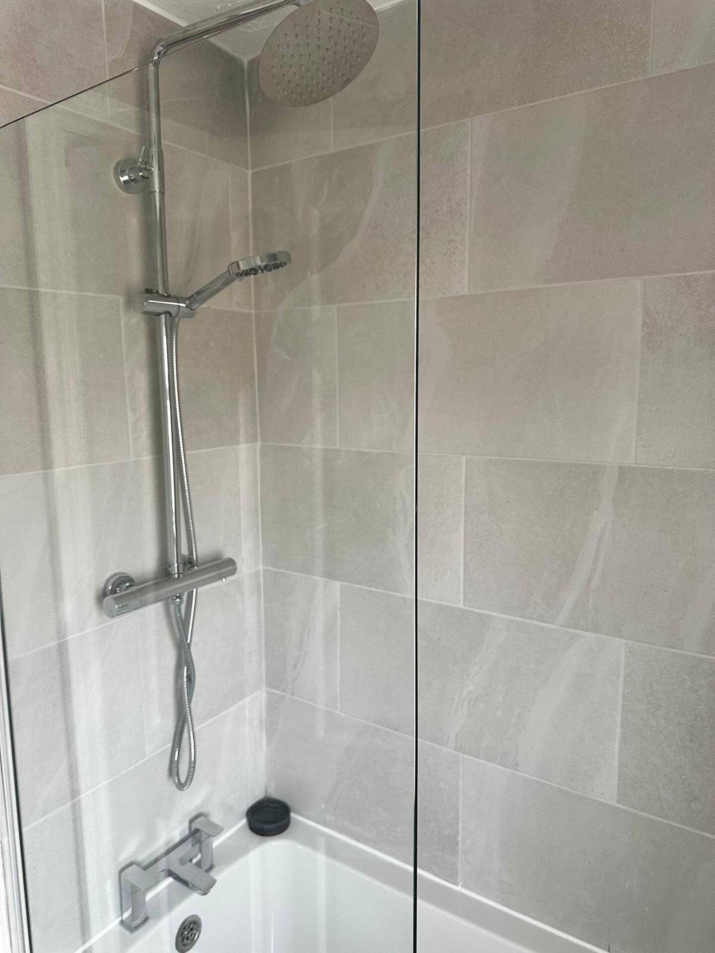 Een douche met een handdouche en een wandmengkraan.