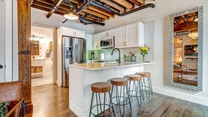 A modern kitchen with white cabinets, a stainless steel refrigerator, and a central island with stools.