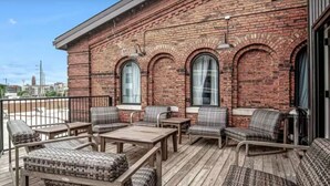 A brick building with a wooden deck, outdoor seating, and large windows.