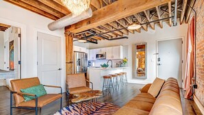 A spacious living area with a leather sofa, a patterned rug, and a wooden ceiling.