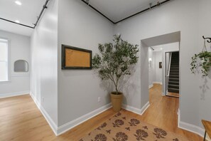 A hallway with a potted plant, a framed picture, and a patterned rug.