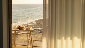 Vista del océano desde una habitación con una mesa lista para el desayuno.