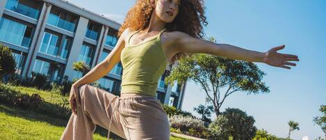 A person performing a yoga pose on a mat outdoors with a building in the background.
