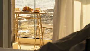 Un balcón con una mesa preparada para el desayuno y vista al mar.