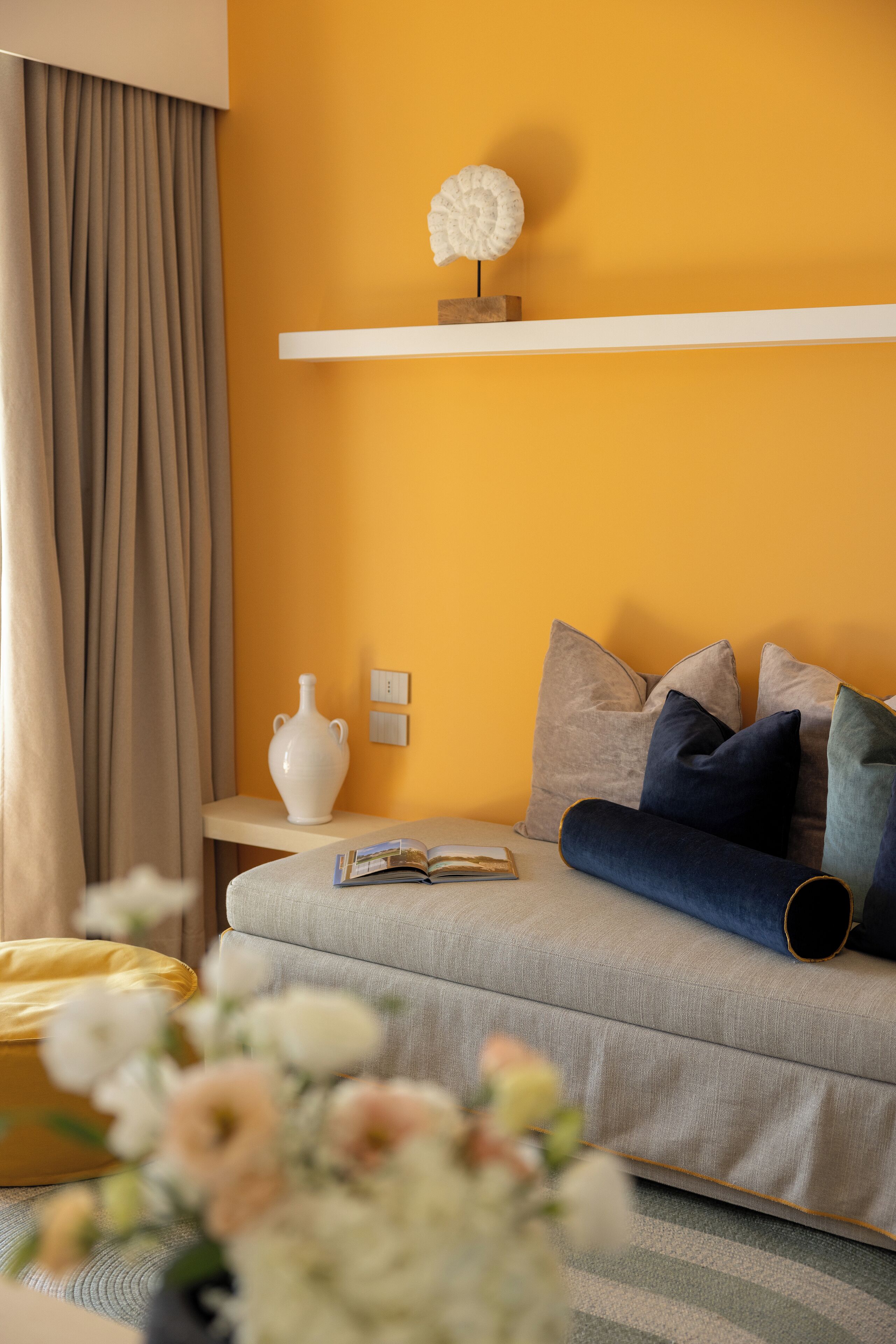 A modern living room with a sofa, decorative pillows, a vase, and a book on a side table.