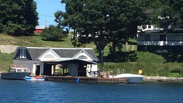 A docked boat near a house with a covered porch and a small dock extending into the water. - Spacious Grindstone Island House across from Clayton, NY (Clayton)
