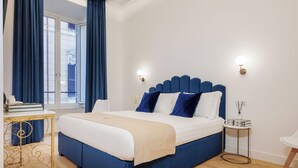 A bedroom with a large bed, a desk, a chair, a window with curtains, and a decorative ceiling. - SM Mellini Relais (Rome)