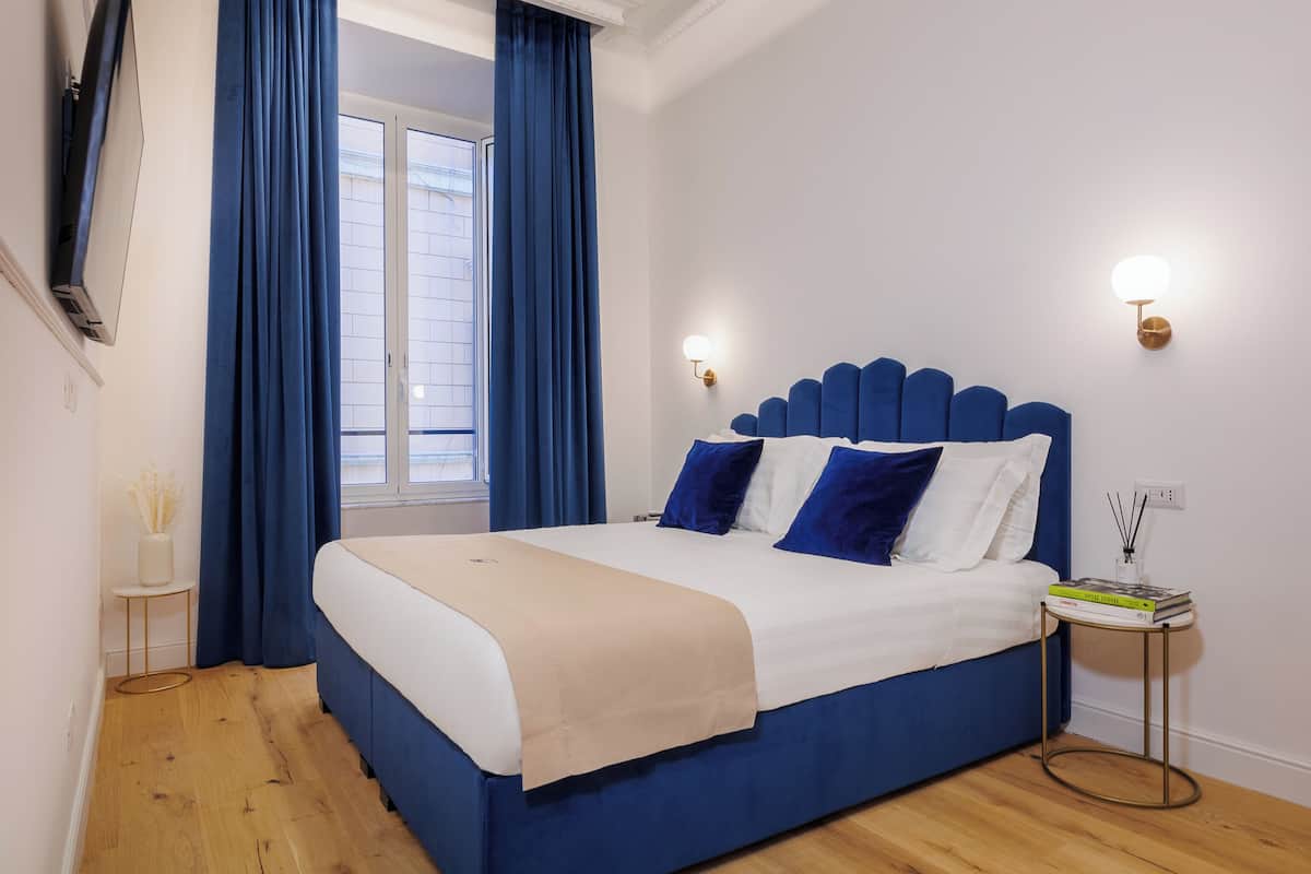 Un dormitorio con una cama grande, cortinas azules, suelo de madera y techo decorativo.