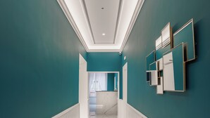 A hallway with teal walls, white wainscoting, and a marble floor. - SM Mellini Relais (Rome)