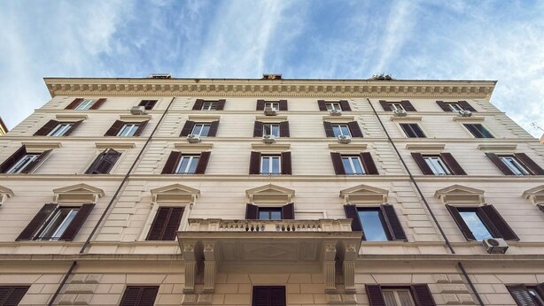 A multi-story building with a classical architectural style, featuring a central entrance with an arched doorway and multiple windows with shutters. - SM Mellini Relais (Rome)