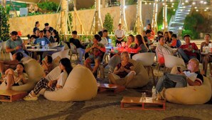 An outdoor seating area with round bean bags and tables, surrounded by palm trees and a building in the background. - Apec Mandala Mui Ne - Sapphire Apartment (Mui Ne)