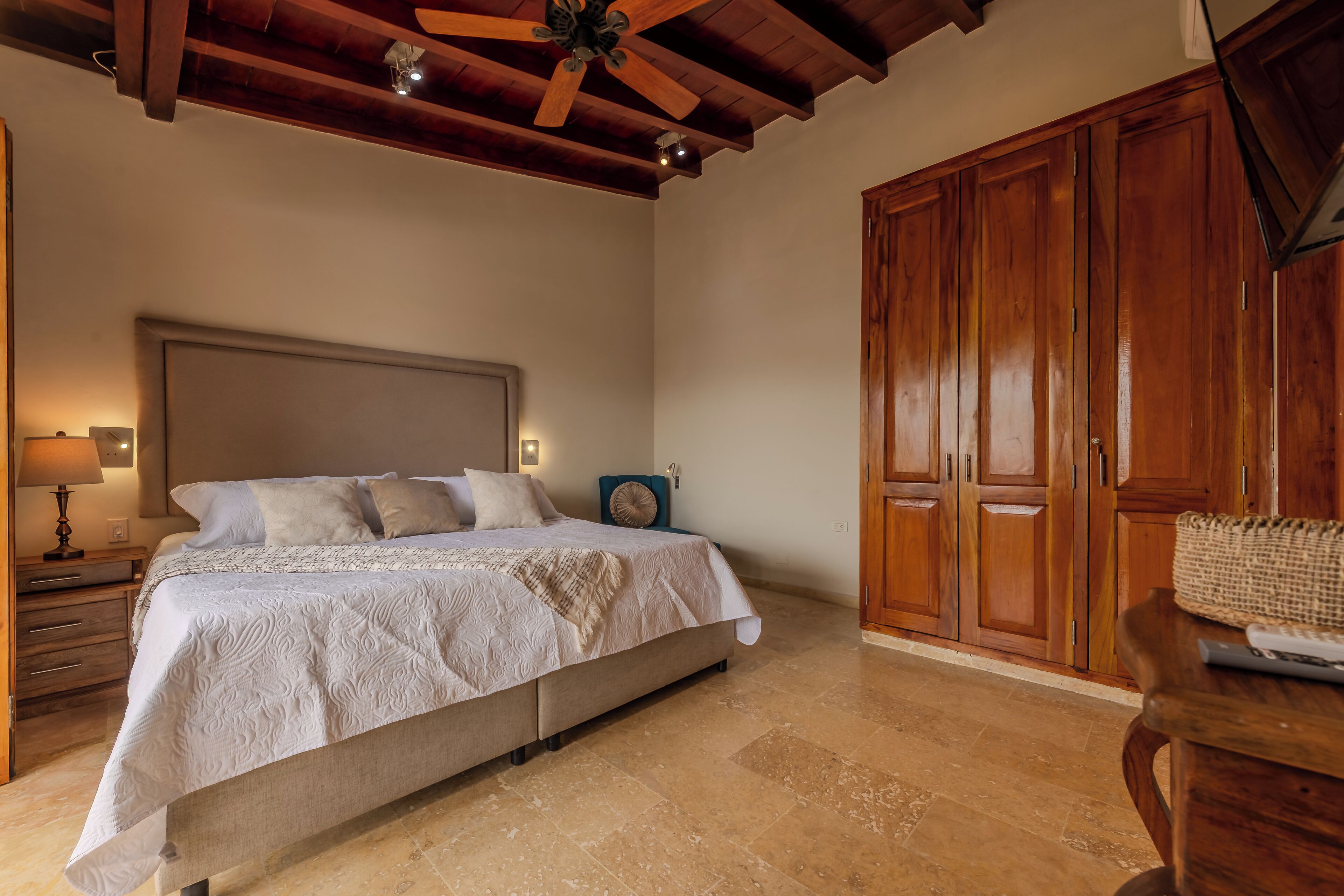 Un dormitorio con cama, armario de madera y ventilador de techo.