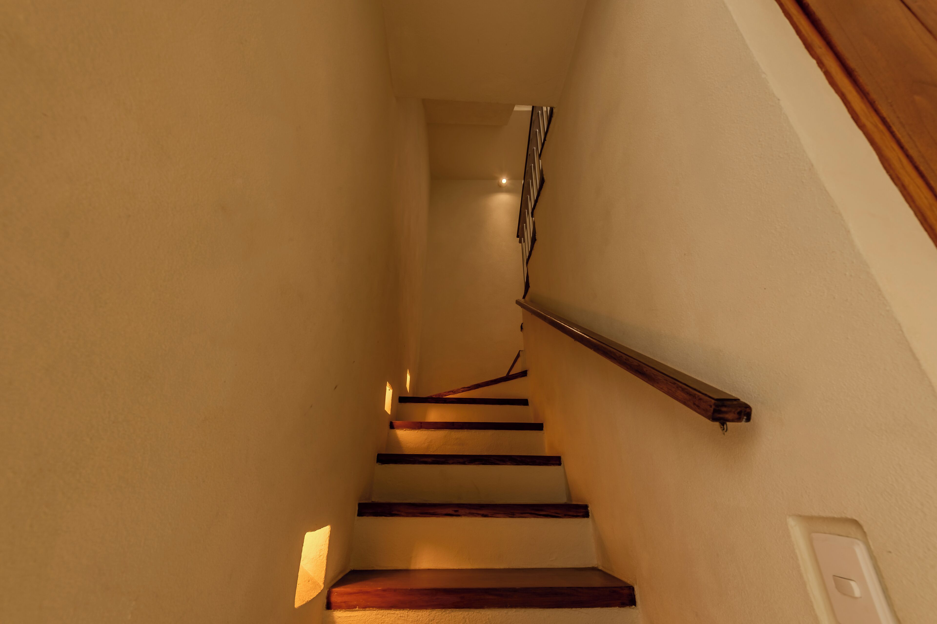 Una escalera de madera con barandilla que conduce a un piso superior.