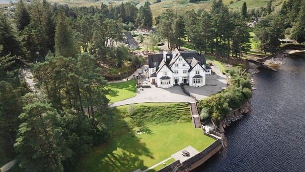 A large, white, Tudor-style house with a spacious lawn and a river in the background. - Stronachlachar Lodge - spacious with cinematic views, direct access to loch. (Stirling)