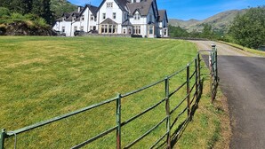 A large white house with multiple chimneys and a spacious lawn in front. - Stronachlachar Lodge - spacious with cinematic views, direct access to loch. (Stirling)