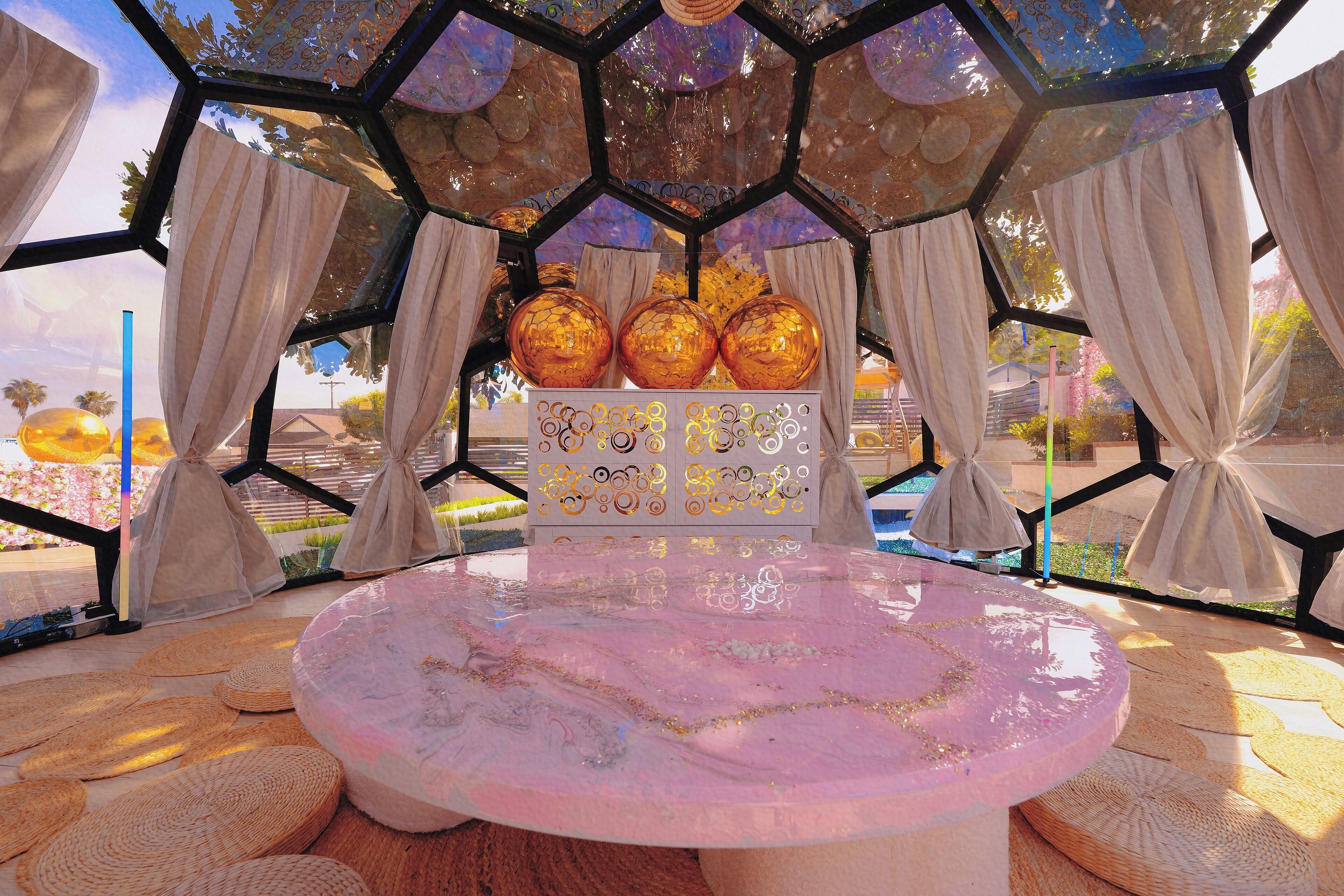 A room with a round table, hexagonal ceiling, and curtains.