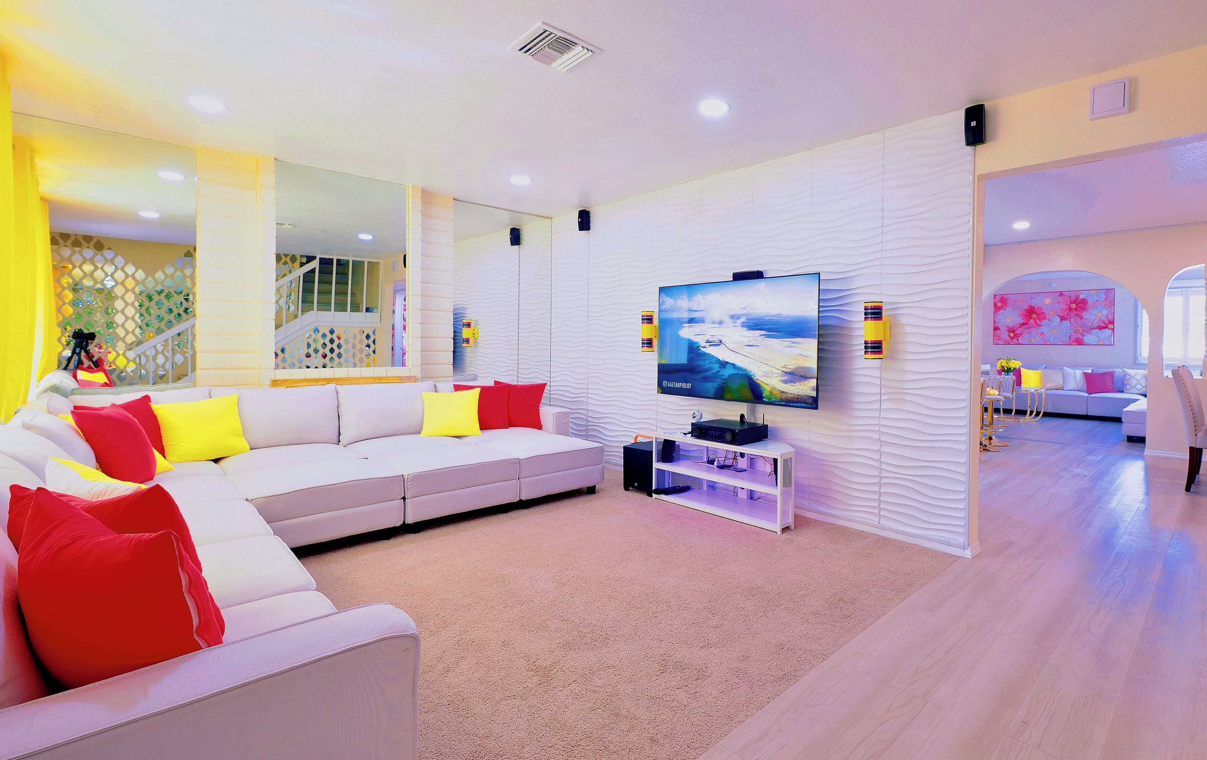 Un salon moderne avec un canapé blanc, un téléviseur à écran plat et un miroir décoratif.