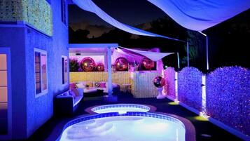 Area piscina con idromassaggio, zona relax coperta con cuscini e decorazioni come palloncini e una tenda bianca.