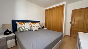 A bedroom with a bed, nightstands, a wooden wardrobe, and a door. - Lovely Holiday Place with pool, A/C, TV, WIFI - Playa Sol Vinaros (VC)