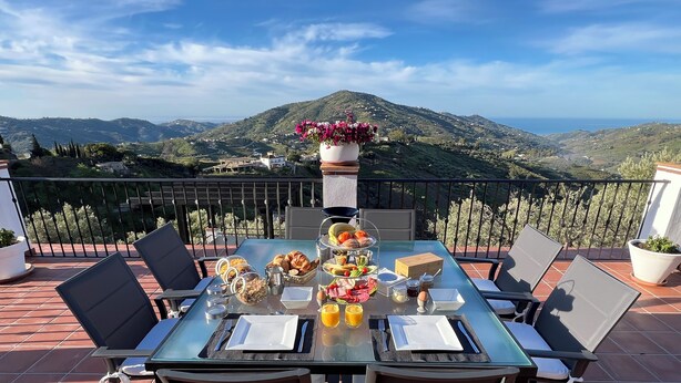 A table set for breakfast on a terrace with a scenic view of hills and the sea. - Villa El Dorado B&B and Wellness (Competa)