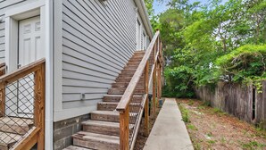 A wooden staircase with a metal railing leading to a white door.