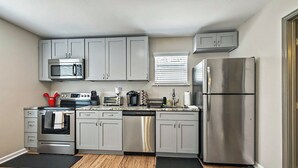 A modern kitchen with grey cabinets, stainless steel appliances, and a wooden floor.