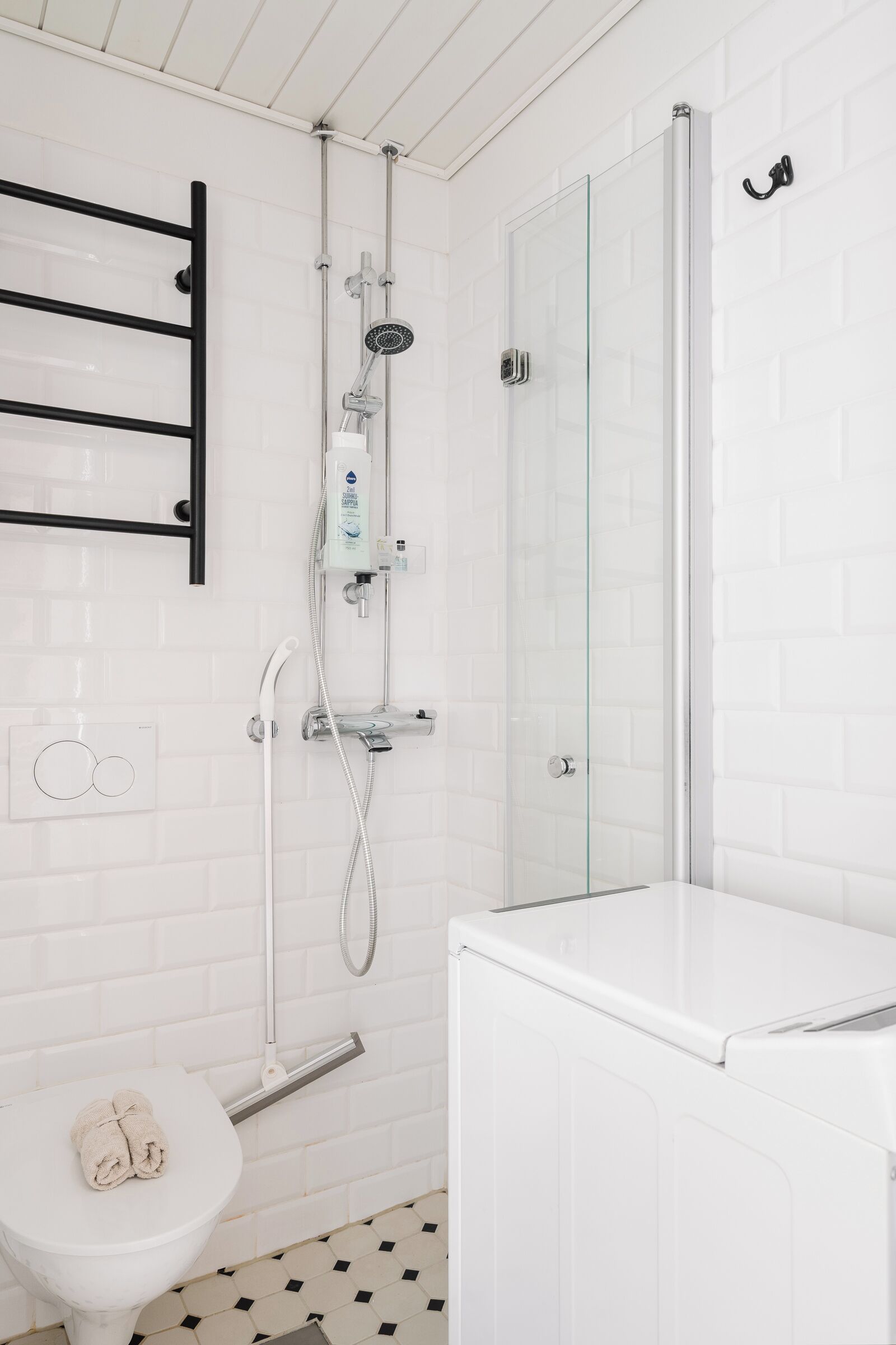A bathroom with a white toilet, a glass shower enclosure, and a white sink.