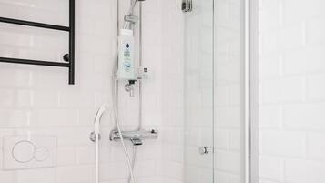 Een badkamer met een wit toilet, een douchecabine van glas en een witte wastafel.