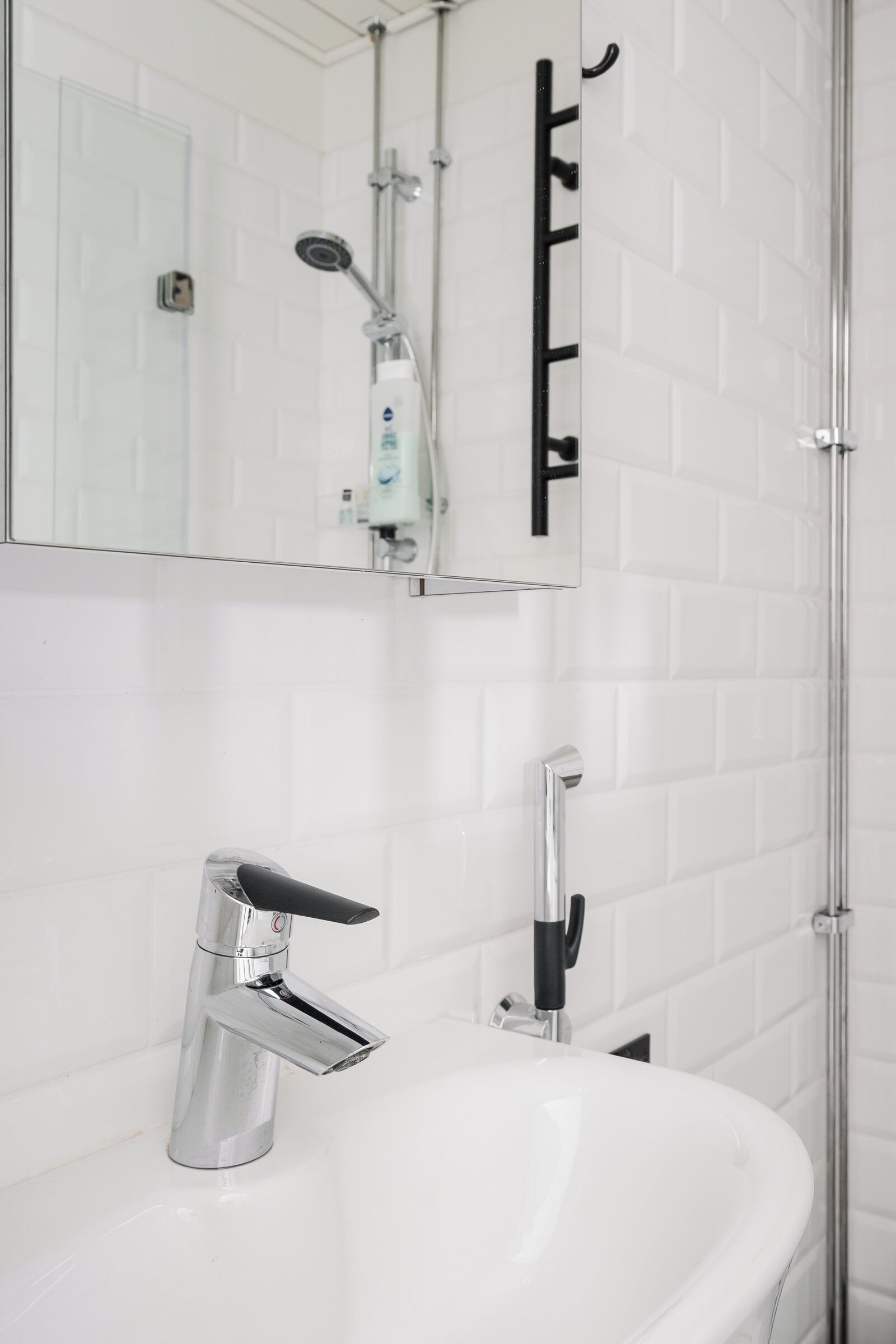 A bathroom with a white sink, chrome faucet, and a mirror above it.