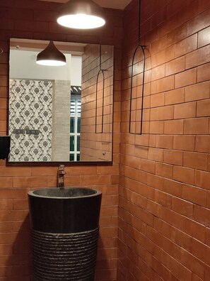 Bathroom features a large round sink and a rectangular mirror with a decorative frame.