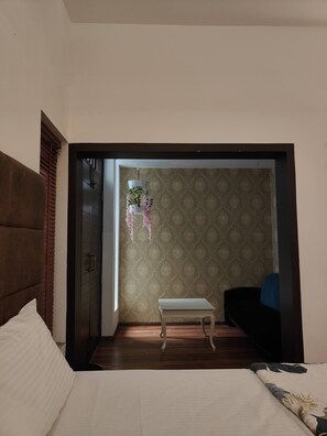 Relax in this serene bedroom with a large bed, wooden floor, and comfortable bench.