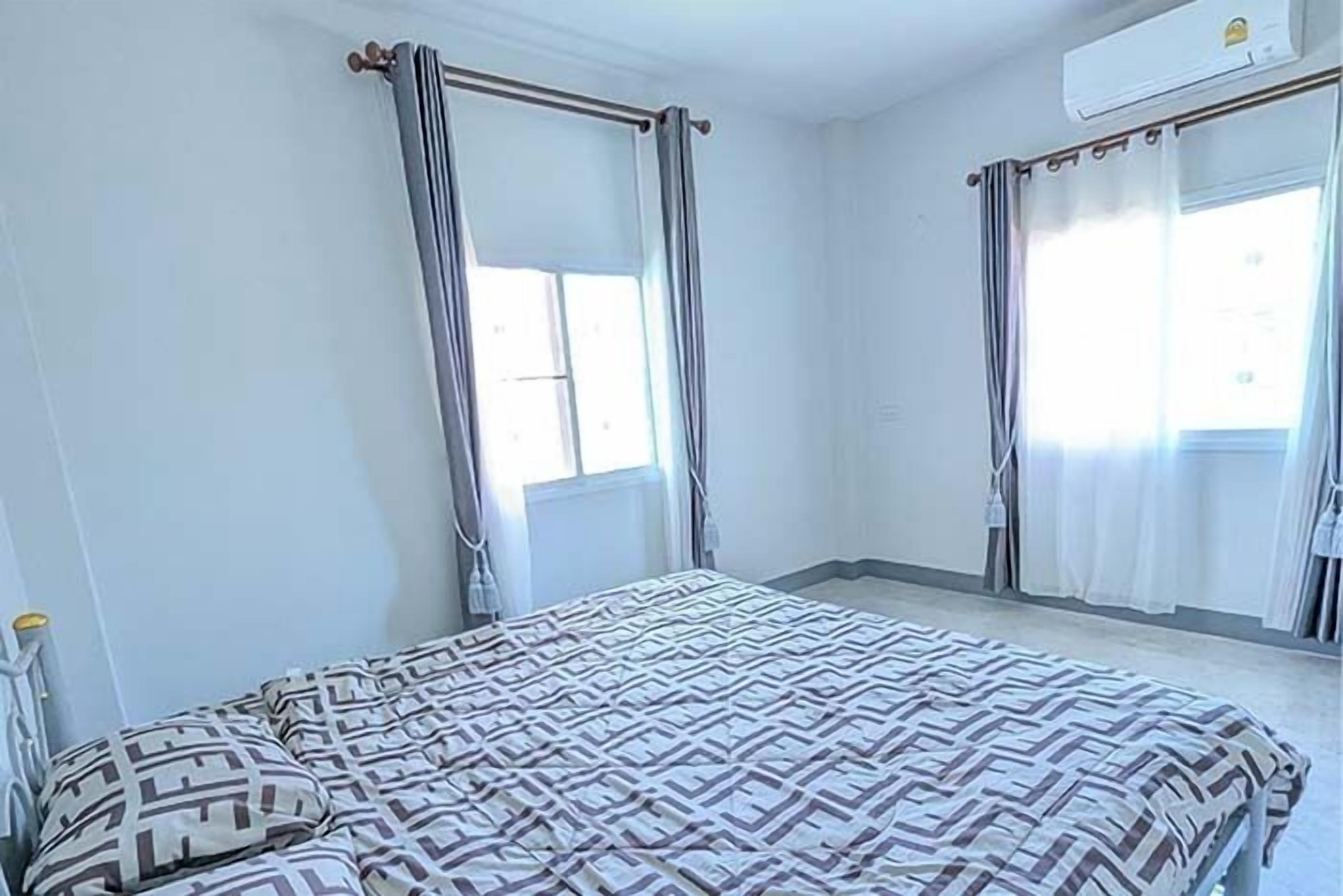 A bedroom with a bed, curtains, and an air conditioning unit.