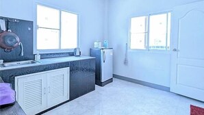 Cocina compacta con lavabo, estufa y refrigerador. Dos ventanas dejan entrar luz natural.