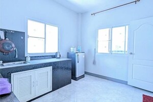 A compact kitchen with a sink, a stove, and a refrigerator. There are two windows providing natural light.