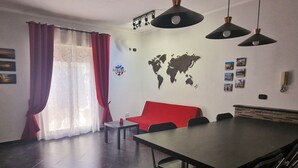A dining area with a red sofa, a large table, and two pendant lights.