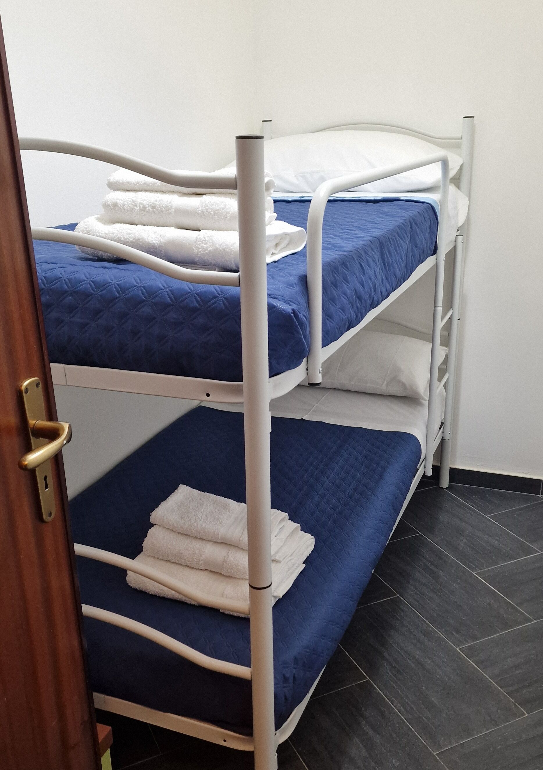 Una cama litera con ropa de cama azul y toallas blancas.