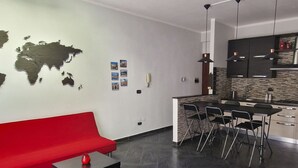 A modern kitchen with a dining area, a red sofa, and a world map on the wall.