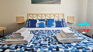 A neatly made bed with a blue and white patterned bedspread, two pillows with a blue and white design, and a pair of folded towels on the bed.