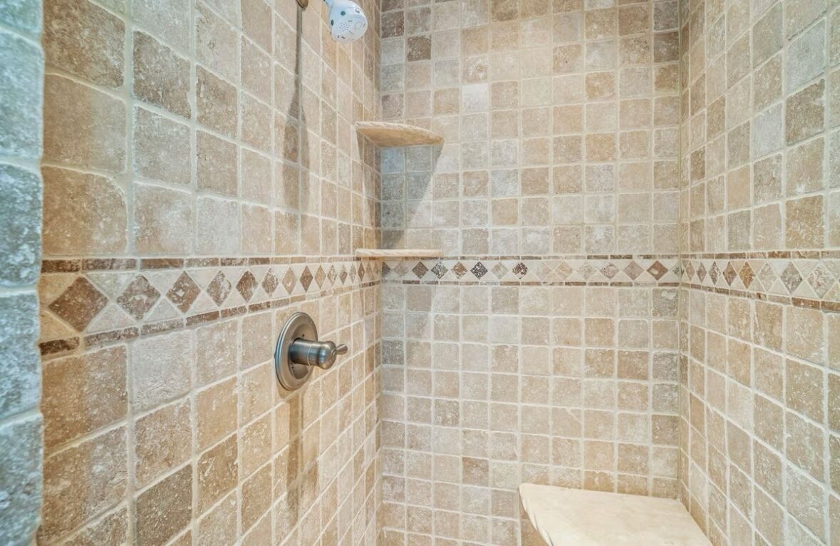 Zona de ducha con paredes de azulejos y ducha de metal.