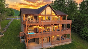 Een houten chalet met twee verdiepingen, een balkon, een hottub en een stenen fundering.