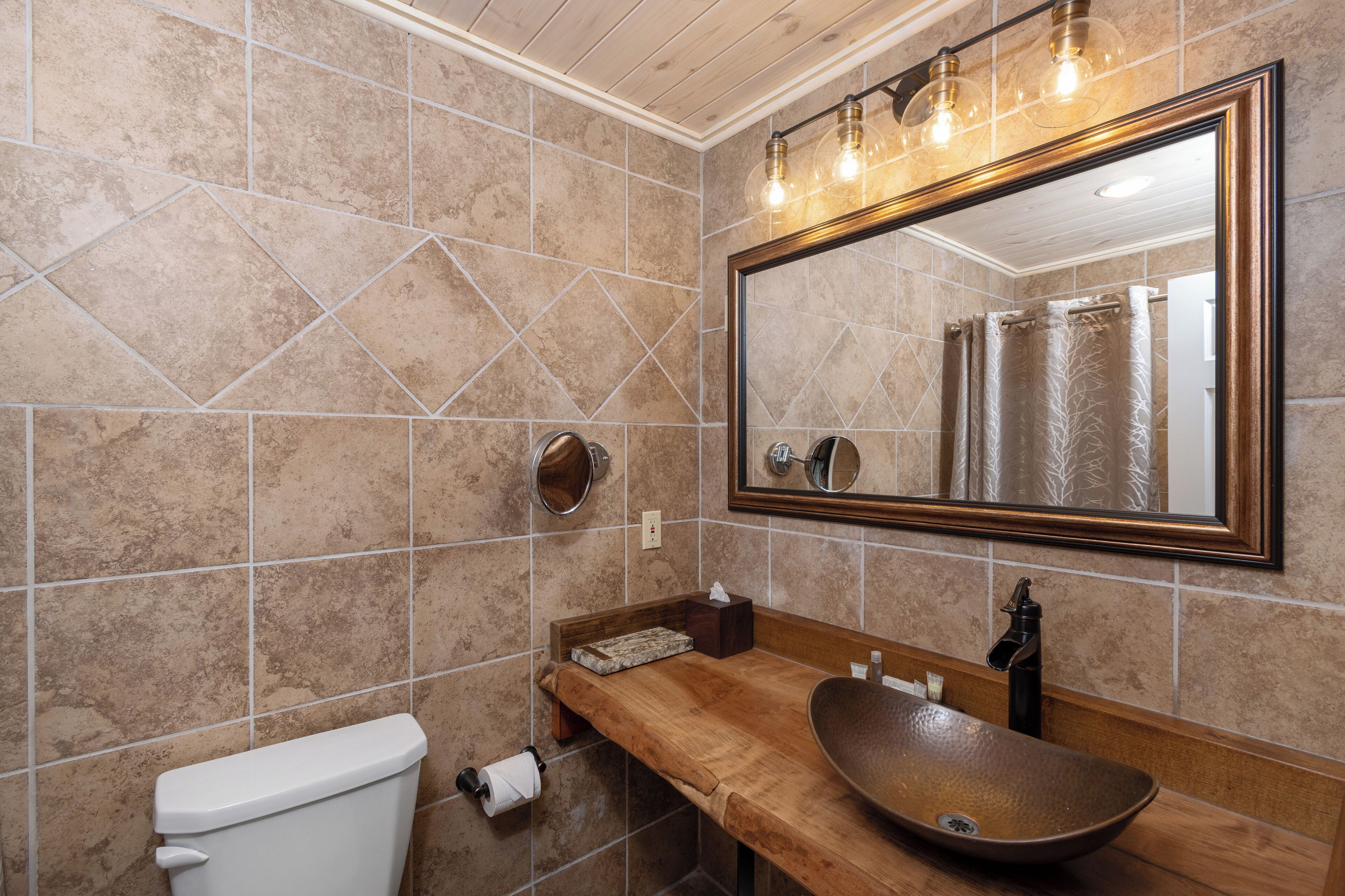 Une salle de bain avec un meuble-lavabo en bois, un grand miroir et des toilettes.
