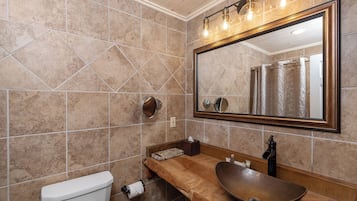 Un baño con tocador de madera, un espejo grande y un inodoro.