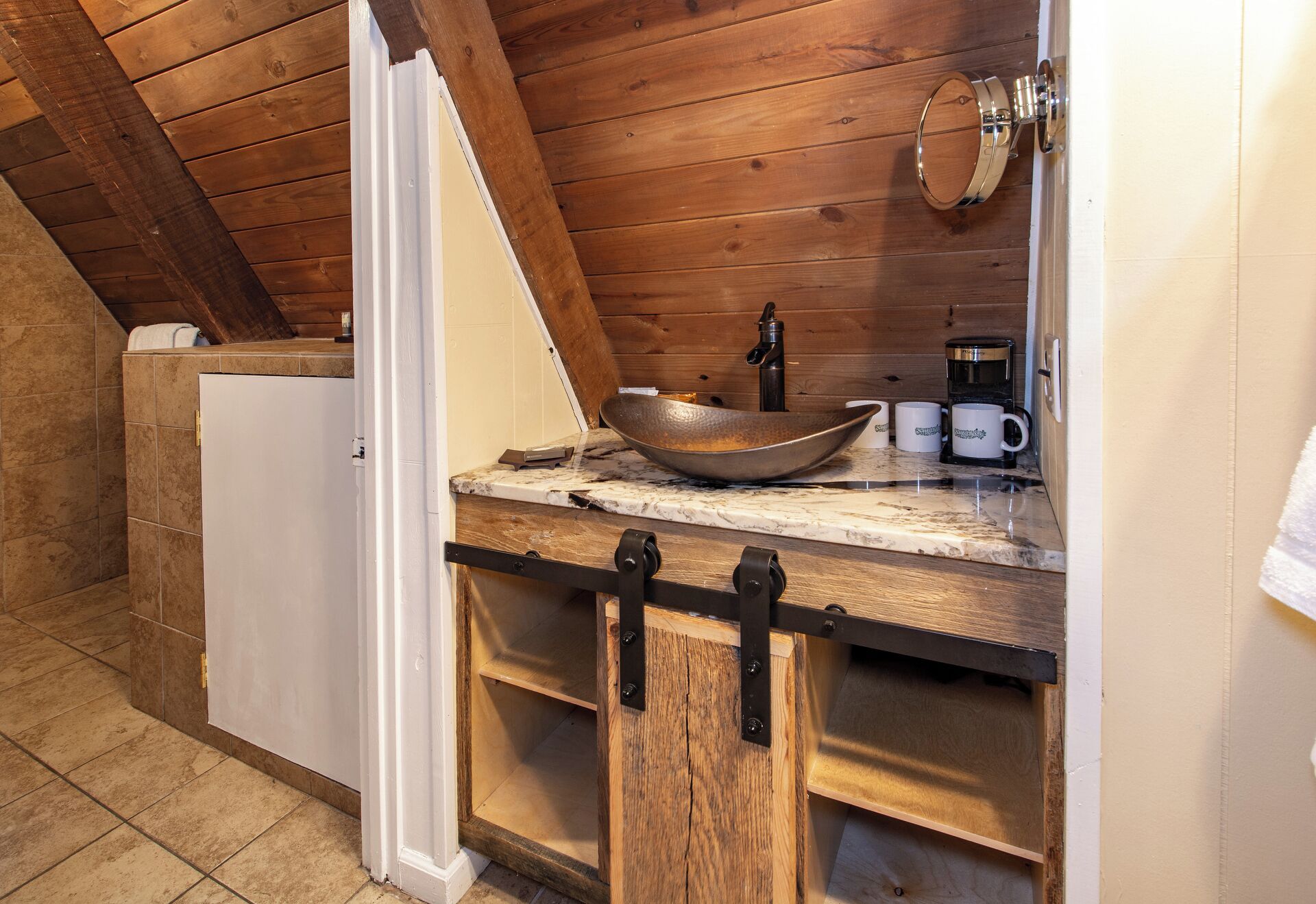 A rustic kitchen with a wooden countertop, a large bowl sink, and a coffee maker.