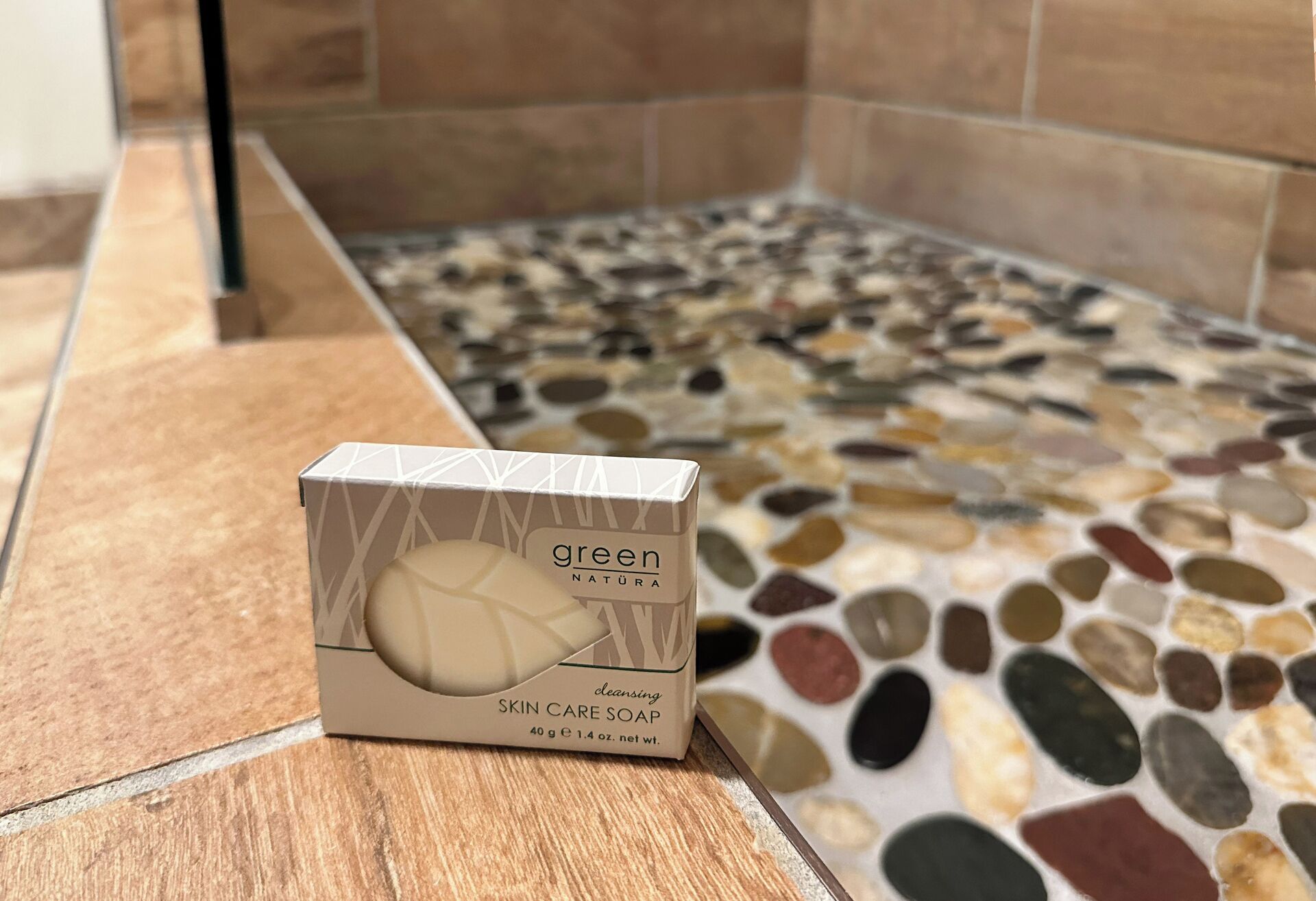 Eine Schachtel mit grüner Natura Hautpflegesseife auf gefliestem Boden.