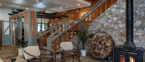 A cozy interior with a stone fireplace, wooden staircase, and comfortable seating area.