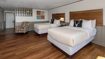 Una habitación de hotel con dos camas, una silla y suelo de madera.