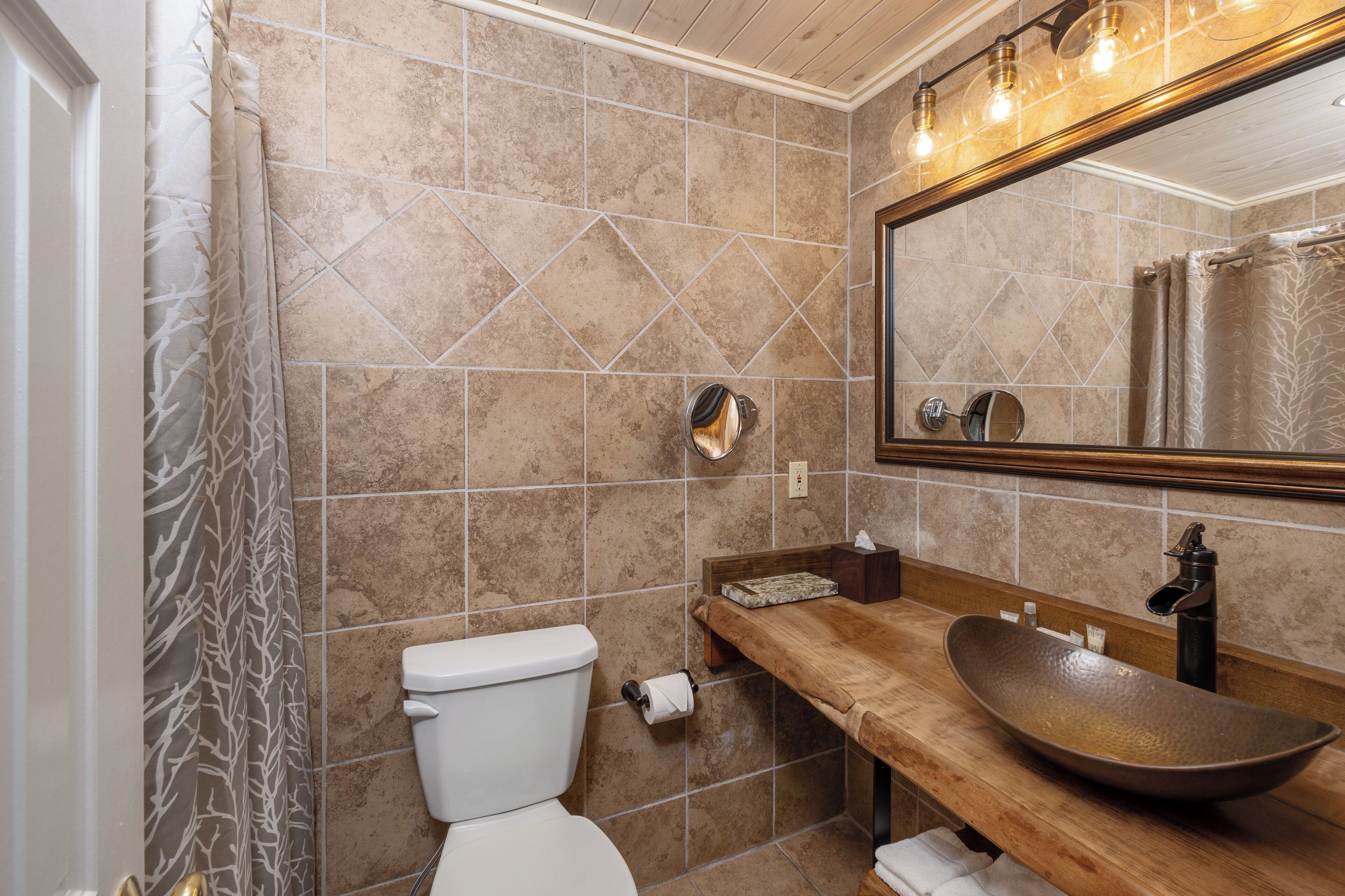 Een badkamer met een toilet, een houten wastafelmeubel, een grote spiegel en een wasbak.