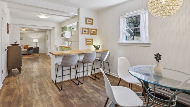 Une cuisine moderne avec un îlot central en bois, des tabourets de bar et une table à manger en verre.
