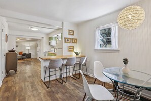 A modern kitchen with a wooden island, bar stools, and a glass dining table. - Chic Converted Barn w/ 2 BR & 2.5 BA in Covington, LA (Covington)