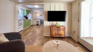 Un salon moderne avec un téléviseur à écran plat, un meuble en bois et une table basse ronde.